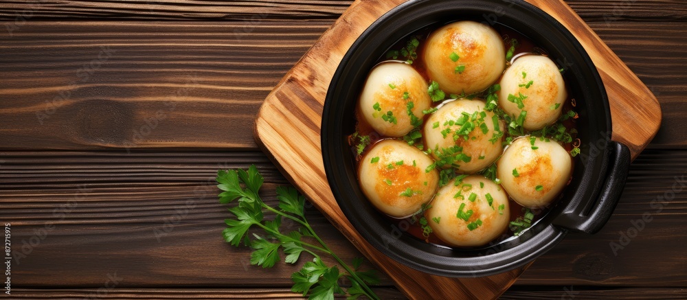 Poster top view of potato dumplings fried in a clay pot on a wooden background with copy space image.
