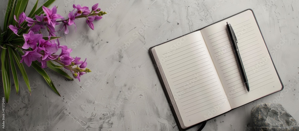 Aufkleber Flat lay with a notebook, a pen, and a purple flower arranged on a gray backdrop, seen from a top view, creating a composition with copy space image.
