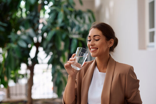 Young happy businesswoman drinking water in  office.