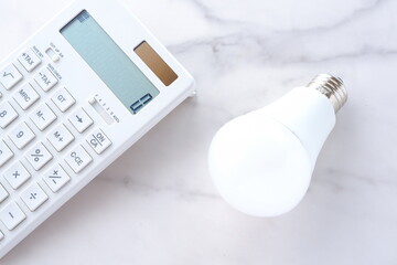 電卓と電球で、高騰する電気代のイメージ
