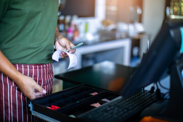 Selective focus to Cashier take slip with blurry banknote in POS. Cash on cashier's desk. Hand giving cash. payday paying cashier access. 