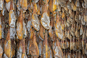 Background of hams, hanging pork leg curing in a drying room
