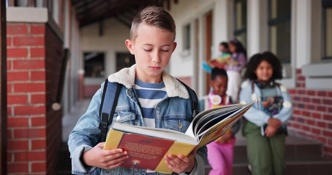 Learner, boy and reading book in school for learning, education and development as student in outdoor. Male child, serious and confident for growth, skills and scholarship in literacy or numeracy