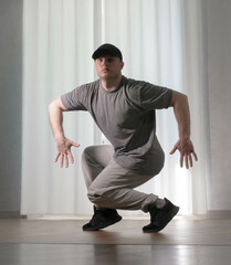 Dance in motion, pose of a man in hip-hop style clothes. Sports dancing guy in training poses. Dance training at home.