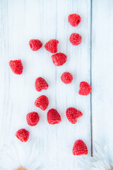 Ripe red raspberries on a white wooden background