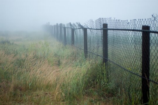 A chain-link fence going into the foggy distance