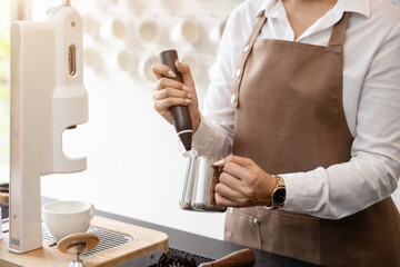 Female barista in apron using blender to froth milk Making coffee for customers in a coffee shop ,small business idea