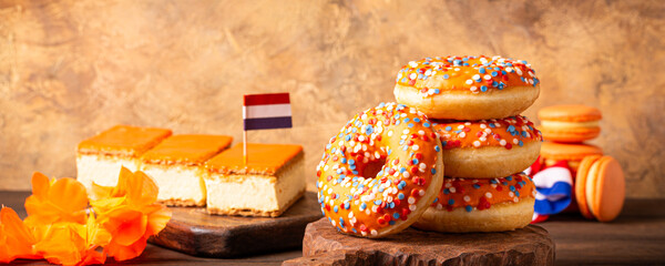 Banner with glazed orange Dutch desserts tompouce and donuts for event Kings day. National holiday...