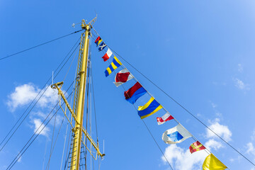 A close-up of a ship's mast with colorful signal flags flying
