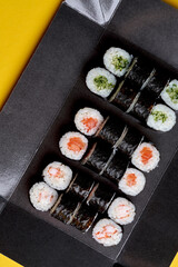 A set of maki rolls with salmon, cucumber, shrimp in a black package. Photo for delivery