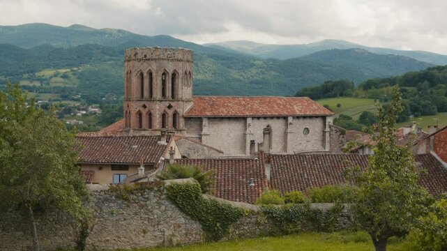 Saint Lizier Cathedral during cloudy day in Occitanie, France. Pyrenees mountains at background.