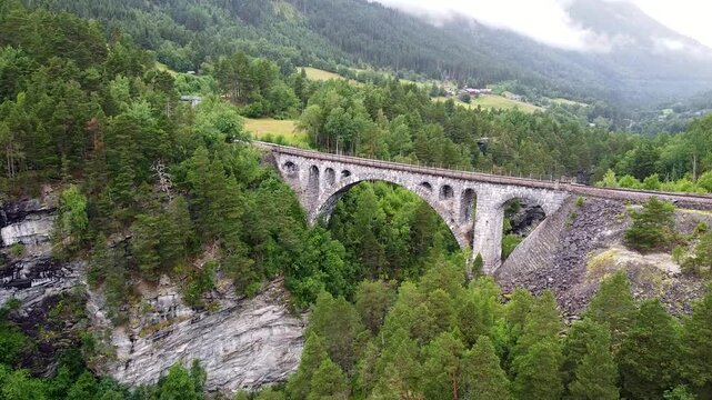 Aerial footage of Kylling Bridge, surrounded by lush forests and mountains, showcasing its architectural beauty and scenic surroundings.