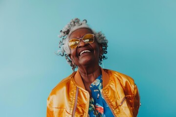Obraz premium Portrait of a grinning afro-american woman in her 80s wearing a trendy bomber jacket over pastel blue background