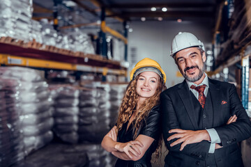 Engineer woman and businessman wearing a hardhat standing cargo at goods warehouse and check for control loading from Cargo freight ship for import and export by report on laptop. Teamwork concept	