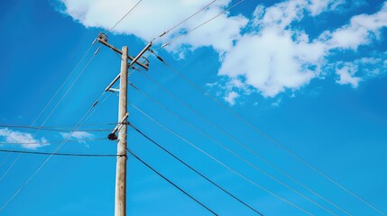 Electric lines against blue sky with hub on pole High voltage wires in background