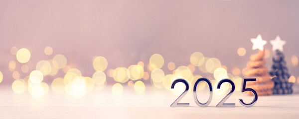 Metal numbers 2025 on a white table with Christmas trees and bokeh lights. Happy New Year 2025 is coming concept.