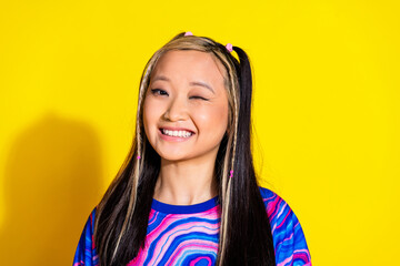 Photo of funny young japanese model with dyed hairstyle showing flirting or blink eye saying oops isolated on yellow color background