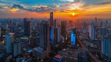 Fototapeta premium Aerial view of Bangkok cityscape around Rama 9 area during sunset, with skyscrapers and streets glowing in bright orange and blue hues.