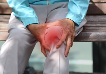 Elderly woman holding her knee with her hand due to pain caused by osteoarthritis
