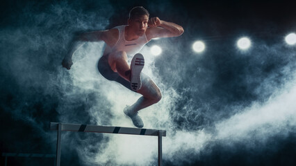 Male Super Athlete Runner in Mid-leap Over Hurdle, Captured in Dramatic Lighting and Smoke. Intense Focus, Agility, and Strength in High-energy Track and Field Event.