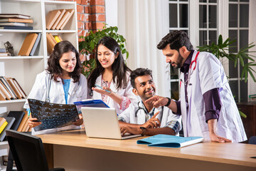Indian asian four young doctors discussing with laptop and case file at table