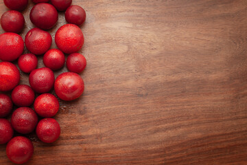 Top-view wallpaper of fresh Cherry Plum (Prunus cerasifera) fruits are arranged on a wooden background.