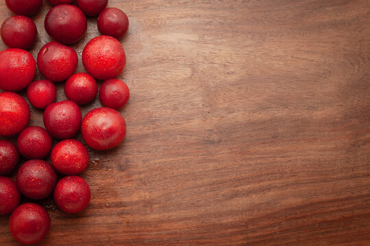 Top-view wallpaper of fresh Cherry Plum (Prunus cerasifera) fruits are arranged on a wooden background.