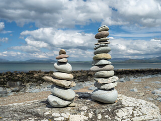 Two piles of zen balanced stones on a sunlit beach