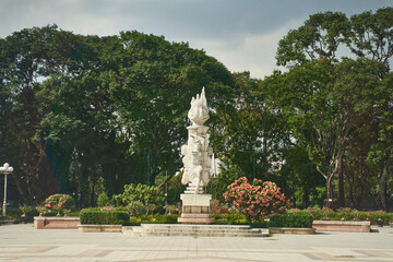 Obraz premium A majestic white horse statue stands proudly in a beautifully landscaped park with lush greenery on a cloudy day