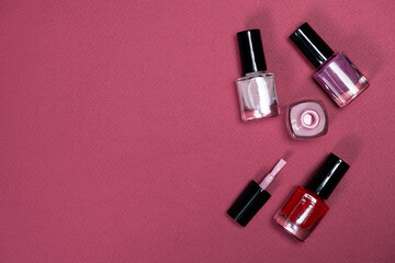 Set of Colorful Bottle Nail Polishes on Pink Background, Space for Text.