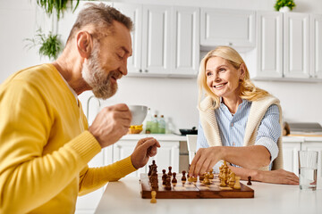 A mature man and woman in cozy home attire engage in a game of chess, deep in thought as they...
