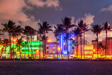 Miami Beach Ocean Drive hotels and restaurants at sunset. City skyline with palm trees at night. Art deco nightlife on South beach