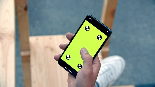 Close-up of iPhone with Green Screen and Tracking Dots, Finger Swiping Upward to Scroll Feed