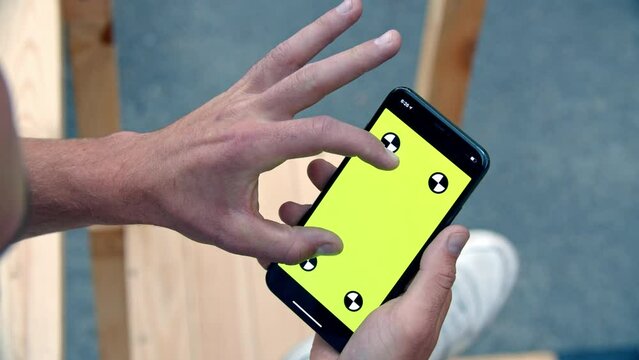 Close-up of iPhone with Green Screen and Tracking Dots, Zooming In with Another Hand