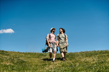 Fototapeta premium Two young men hike together in a beautiful, grassy landscape on a sunny day.