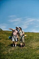 Fototapeta premium A young gay couple hikes through a grassy field under a sunny blue sky.