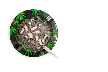 Marijuana joint cigarette on a dirty ash tray with cannabis leaves pattern, flat lay isolated on...
