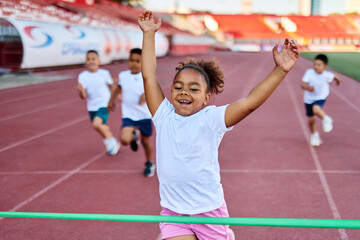 child sport athlete competition running race exercise sprinting speed runner achievement finish line celebration challenge champion goal ribbon success