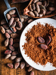 Close-up of Natural cocoa powder with brown cocoa beans and dry cacao pod  on a vintage wooden table.Top view