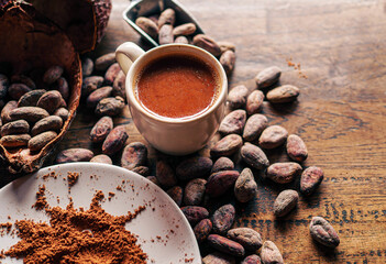 Hot chocolate drink,cocoa drink and natural cocoa powder with brown cocoa beans and dry cacao pod  on a vintage wooden table.