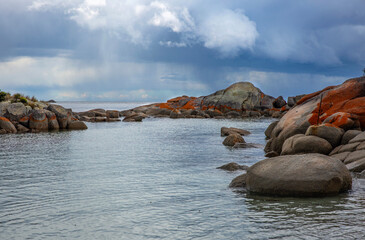Rocky backwater in the Bay of Fires, Tasmania, with rain clouds on the horizon.