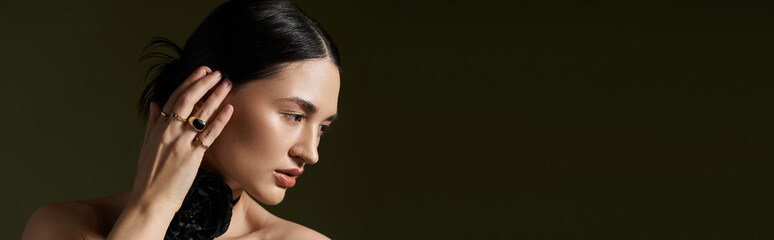 Obraz premium A beautiful woman with brunette hair and a floral choker necklace poses against a black backdrop.