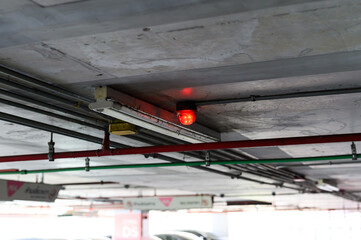 Fire detection system with red lights in a dimly lit parking garage ceiling