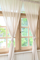 Elegant window with tied-back curtains allowing natural light to fill the room. Window, curtains, natural light, elegant, interior.