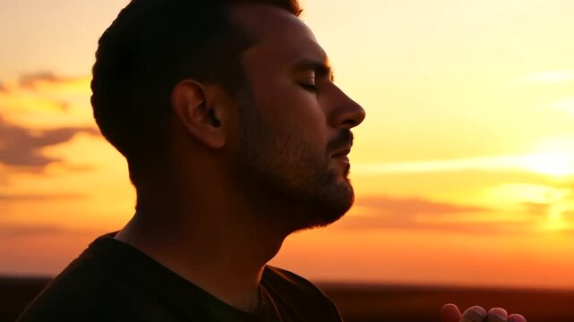 man kneeling in prayer at sunset