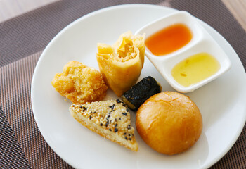 Close up small portion of crispy Dim Sum on a white dish with natural light, baked and deep fried Dim Sum with two types of sauce.