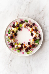 Rosolje - Estonian beet and herring salad or Rosoli Finland salad with boiled beets, potatoes, apples, onions,  herring fish. Midsummer festive food, Summer solstice wreath symbol. Slavic, Scandinavia