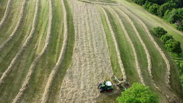 Drohne fliegt &uuml;ber Traktor mit Heuwender, Landwirtschaft, Luftaufnahme