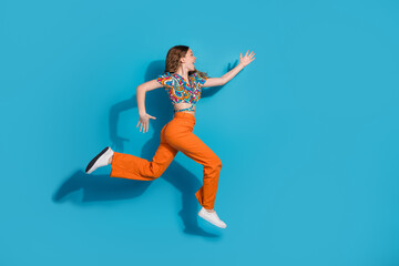 Obraz premium Full size photo of nice young girl jump run empty space wear top isolated on blue color background