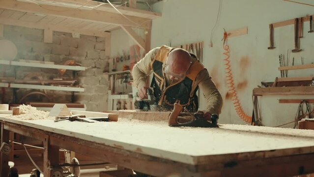 Wood, sander and carpenter in workshop with tools for furniture, production or construction project. Handyman, building and woodworking process in warehouse with manufacturing or labor in business	
